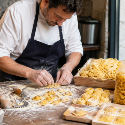 Chef préparant des pâtes artisanales dans une cuisine traditionnelle.