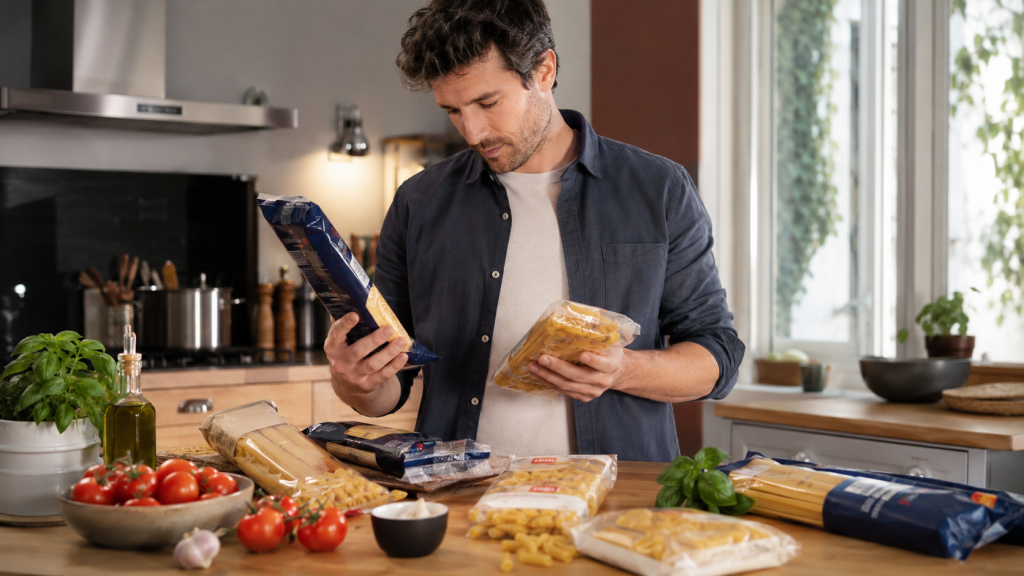 Homme choisissant entre plusieurs marques de p&acirc;tes dans une cuisine moderne.