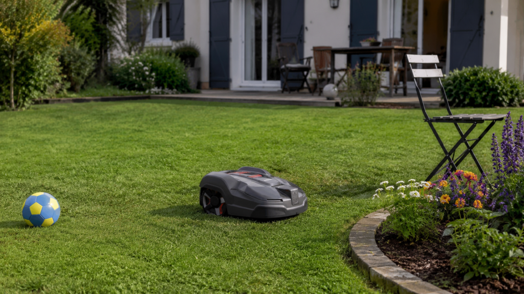 Robot tondeuse sans fil dans un jardin près d'une maison