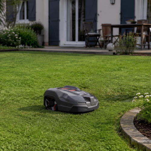 Robot tondeuse sans fil dans un jardin près d'une maison
