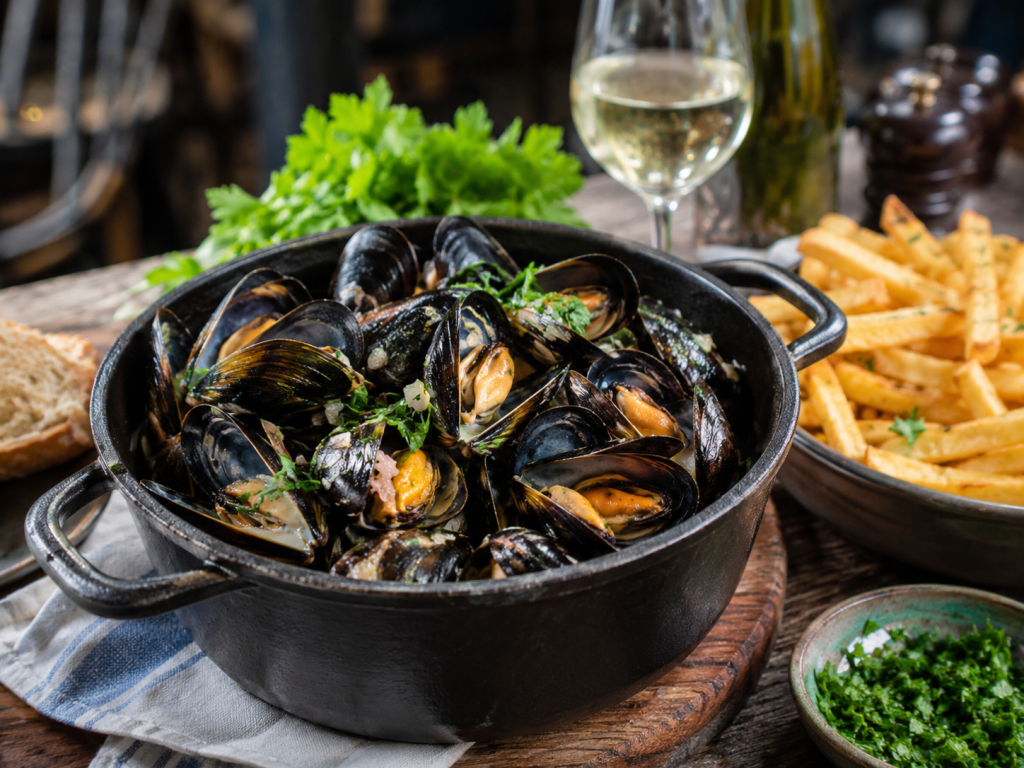 Moules à la marinière servies avec frites maison sur une table en bois
