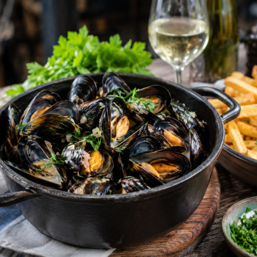 Moules à la marinière servies avec frites maison sur une table en bois